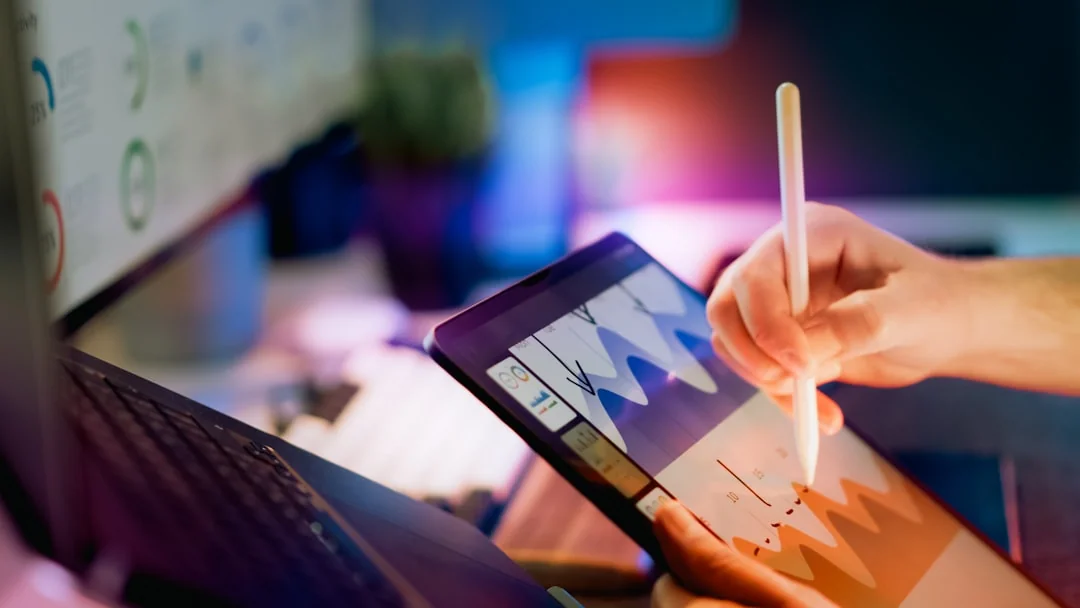 A diverse team collaborating on digital marketing strategies at a desk, using laptops and tablets.